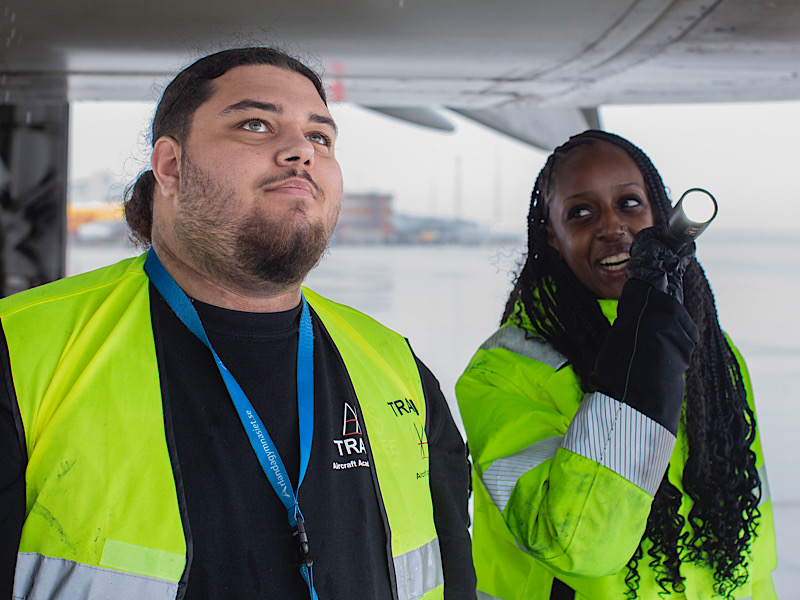 Två ungdomar under ett flygplan.