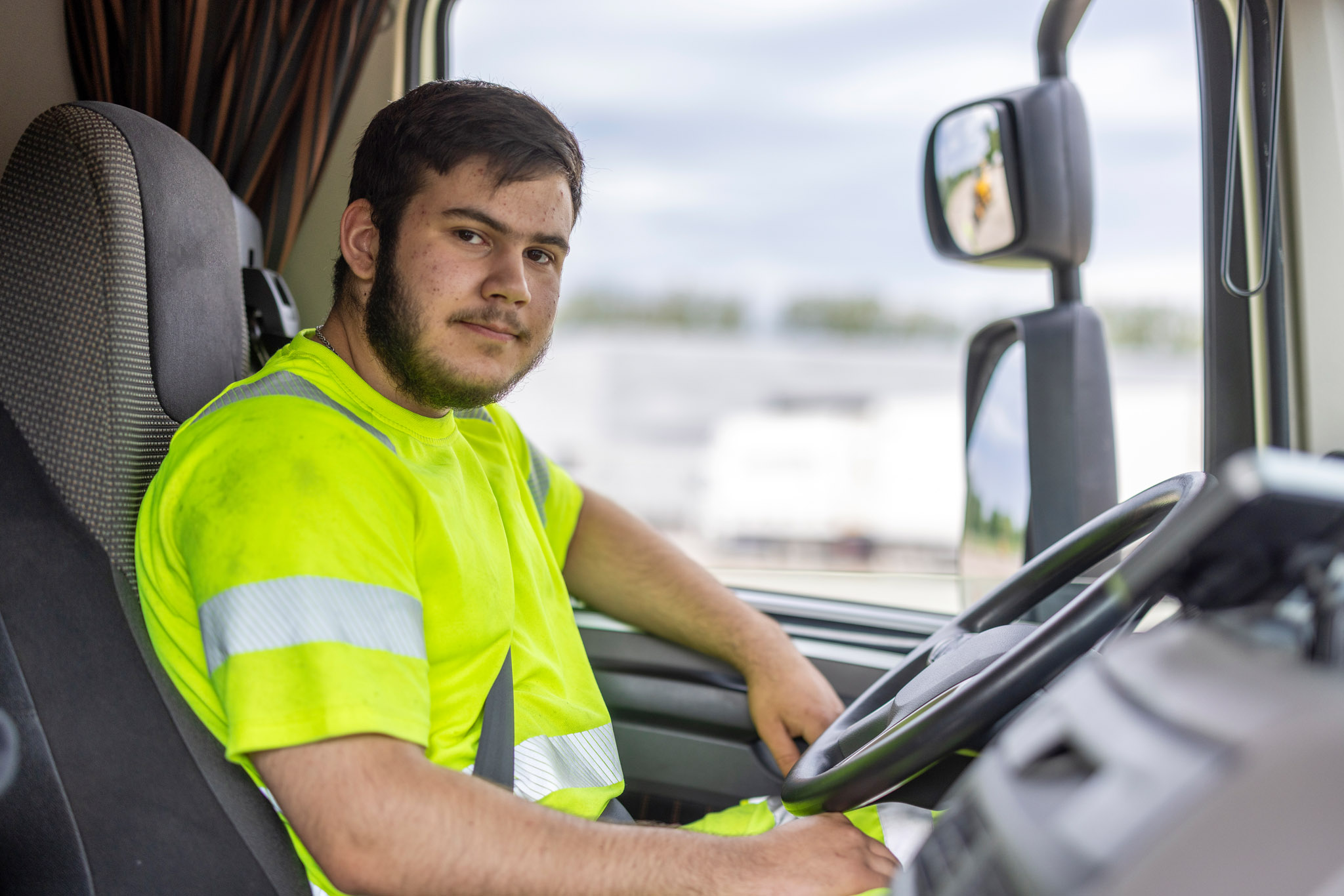 Ung man som sitter bakom ratten i en lastbil.