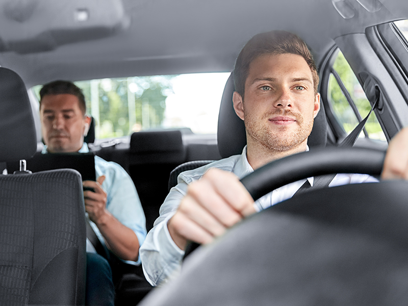 male taxi driver driving car with passenger