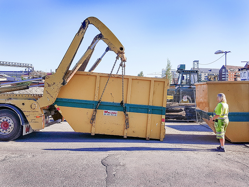 Miljöarbetare lastar av container med liftdumper