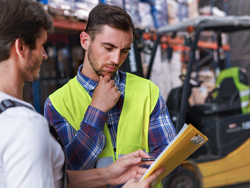 Workers discussing something and standing in warehouse.